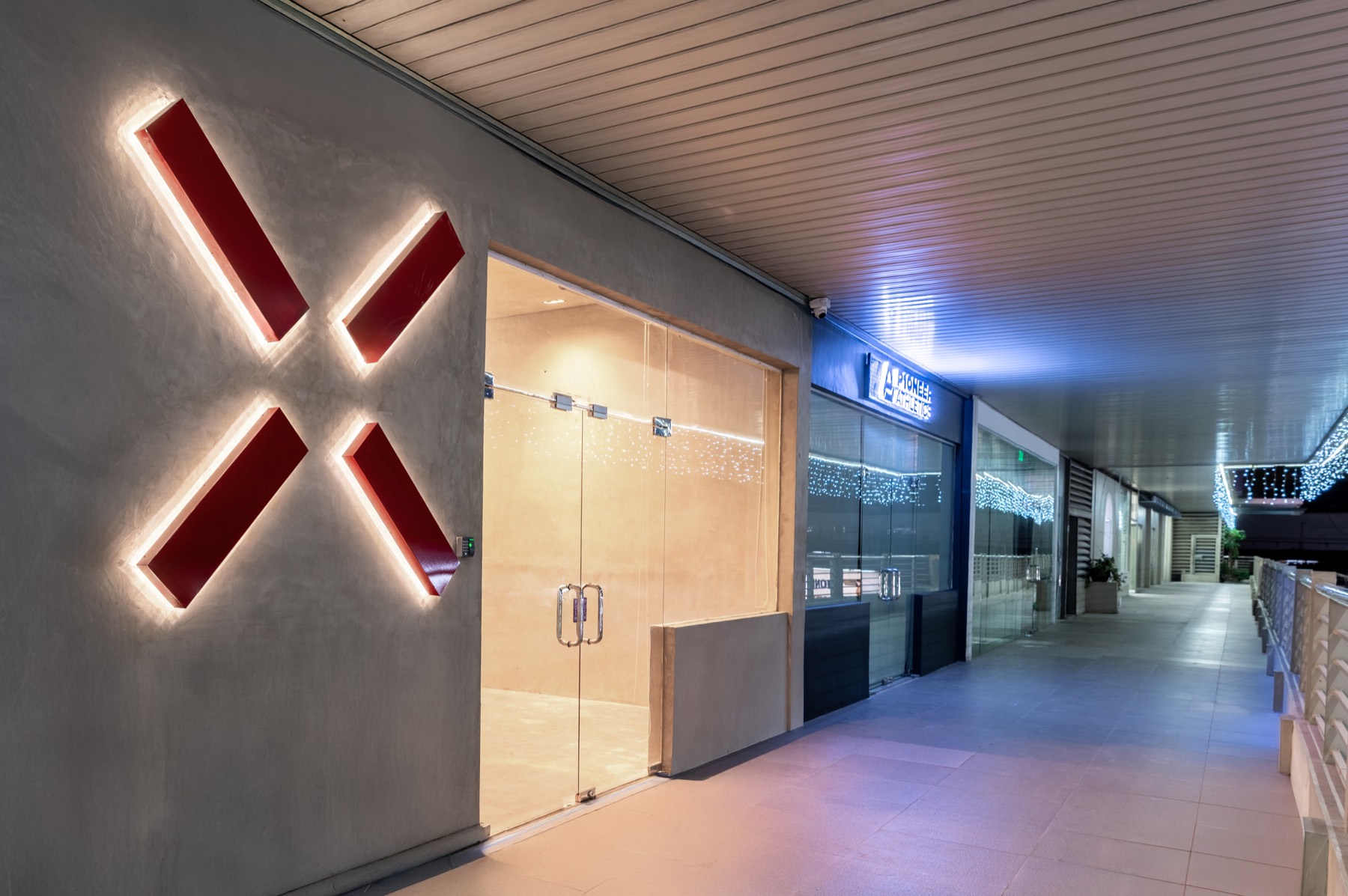PioneerX Studios entrance at 2F Pioneer Centre: glass double doors beside the lit red X logo on the second floor walkway